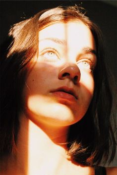 a woman is looking up at the sky with her eyes closed and sun shining on her face