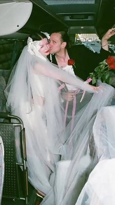 a bride and groom kissing in the back of a car