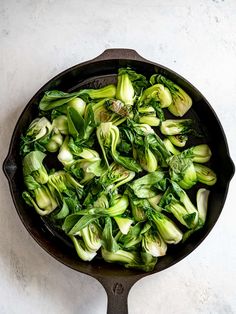 an iron skillet filled with brussel sprouts and other green vegetables