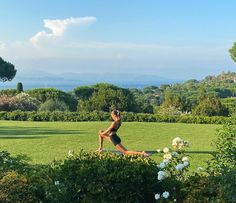 a woman is doing yoga in the middle of a field with white flowers and greenery