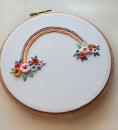 a close up of a embroidery on a white surface with a wooden hoop holding flowers