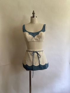 1960s bikini swimsuit by Cole of California is made of crisp white textured cotton with blue cotton scalloped detail. The top buttons in the back and buttons can be moved and re-sewn to adjust the size; straps also button in the back . Skirt zips up in the back and has bloomer like cotton lining under the skirt that are elasticized(elastic is still holding up!). Bathing suit is in excellent condition, no stains or rips. Top: 32" (16" across, doubled)across ribcage(under part of top)-can also be made smaller by removing and resewing buttons Will fit a Bor C cup Bottoms: Waist 27" plus a little bit of stretch from elastic in the back Hips 36" Rise 11" Marauders Dr, Hawaii Holiday, Dr Closet, Under The Skirt, Vintage Swimsuits, Holiday Wear, 1960s Vintage, Women Swimsuits, Bathing Suit