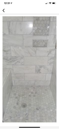 a bathroom with white marble tile and hexagonal pattern on the shower wall, along with a tiled floor