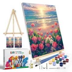 an easel with paint, watercolors and other items for painting flowers on the beach