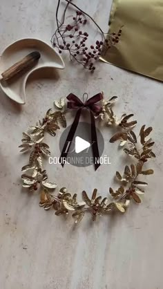 an image of a wreath made out of gold leaves and ribbon on a white table