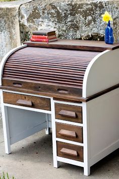 an old desk with drawers and a vase on top is sitting in front of a stone wall