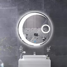 a bathroom sink with a circular mirror above it and a vase on the counter next to it