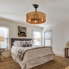 a bedroom with white walls and wood floors, carpeted flooring, two lamps on either side of the bed