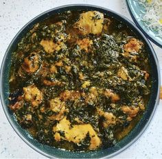 some food is in a blue bowl on a white counter top next to other dishes