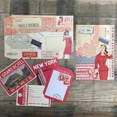 various postcards and envelopes are on a wooden surface, including one with an image of a woman in a red dress