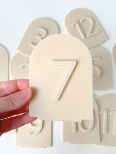 a hand is holding up a white paper with the number seven on it and several smaller numbers behind it