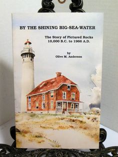 a sign with an image of a lighthouse and the words by the shining big sea - water