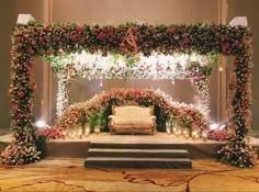 an elaborate stage decorated with flowers, candles and a couch for a wedding ceremony or reception