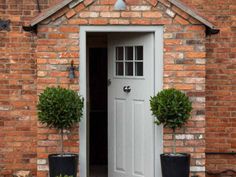 two potted plants in front of a brick building with an open door and window