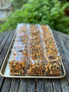 a tray filled with lots of food on top of a wooden table next to trees