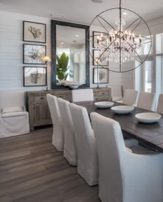 a dining room table with white chairs and a chandelier