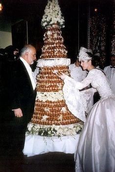 a man and woman standing next to a large cake