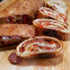 a cut in half sandwich sitting on top of a cutting board next to sliced sausage