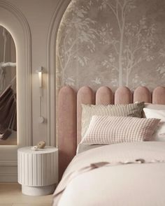 a bed with pink headboard and pillows in a room that has a tree mural on the wall