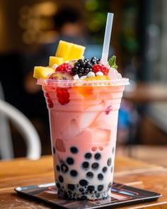 a drink with fruit and ice cream in it on top of a wooden table next to a cell phone