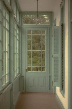 an empty hallway with green doors and windows