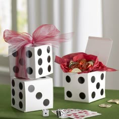 two dice boxes with candy and candies in them on top of a green table