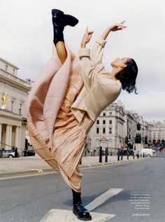 a woman is doing an acrobatic pose on the street