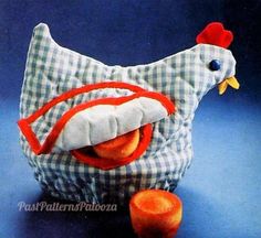 a stuffed chicken sitting next to an orange on a blue tableclothed cloth bag