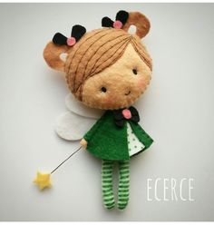 a felt doll with green and white clothes holding a star