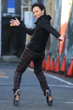 a man in black jacket and plaid pants doing tricks on skateboard with his hands out