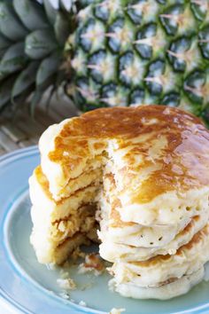 a stack of pancakes sitting on top of a blue plate next to a pineapple