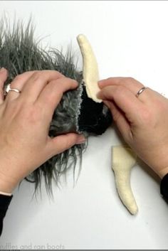 two hands that are holding some kind of animal's hair and scissors to it