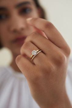 a woman wearing a gold ring with a diamond on it