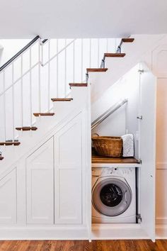 a washer and dryer are under the stairs in this laundry room with wood flooring