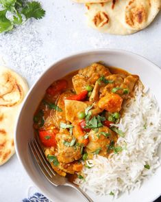 a white bowl filled with rice and curry next to pita bread on the side