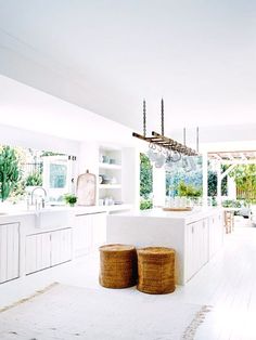 a large kitchen with white cabinets and wooden stools in the middle of the room