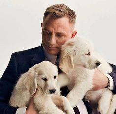 a man is holding two puppies in his arms while wearing a suit and tie