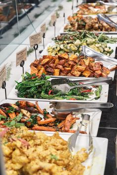 a buffet table filled with lots of different types of food on plates and serving utensils