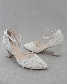 two pairs of white bridal shoes sitting on top of a gray cloth covered floor