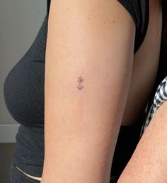 a woman's arm with a small flower tattoo on the left side of her arm