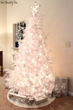 a white christmas tree with presents under it