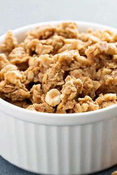 a white bowl filled with granola sitting on top of a blue cloth covered table