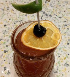 an orange slice is sticking out of the top of a chocolate drink with a green garnish