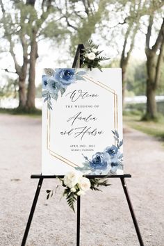 a wedding sign with blue flowers and greenery