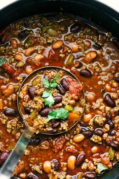 a ladle full of beans and rice in a slow cooker with a spoon