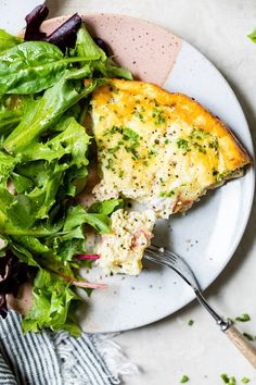 a white plate topped with a slice of pizza next to a green salad