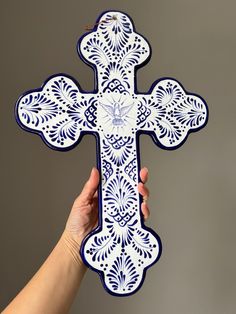 a person holding up a decorative cross shaped paper cutout in the shape of a cross