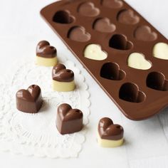 heart shaped chocolates in a muffin pan on a doily next to an empty tray