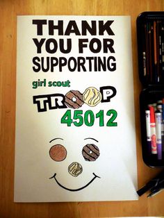 a thank you for supporting girl scout trip poster with markers and crayons next to it