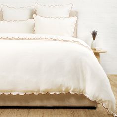 a white bed with scalloped edges and two pillow cases on top of it